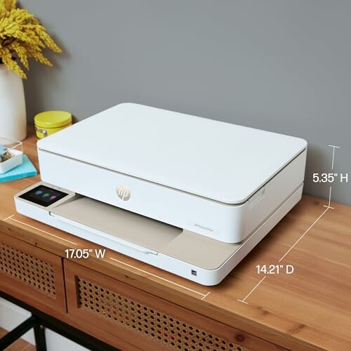 Compact white printer on a wooden desk with dimensions labeled.