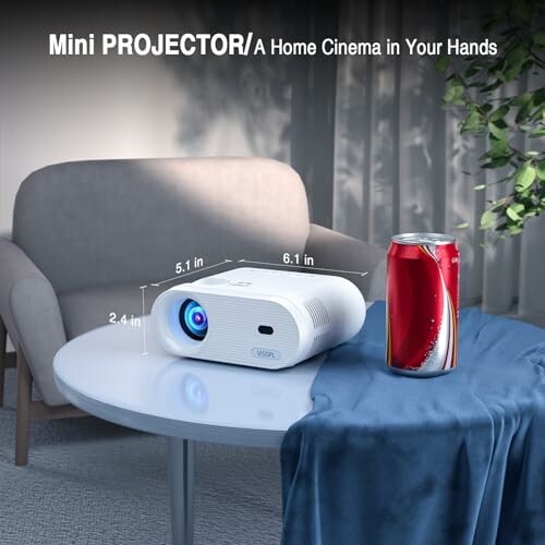 Mini projector on a table next to a soda can and a chair.