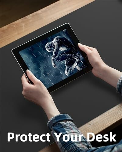 Person holding a tablet over a desk, displaying an image