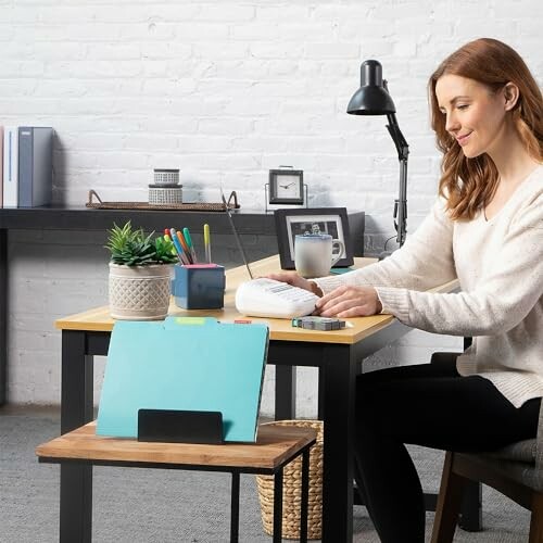 Woman sitting at desk organizing stationery and files in a home office.